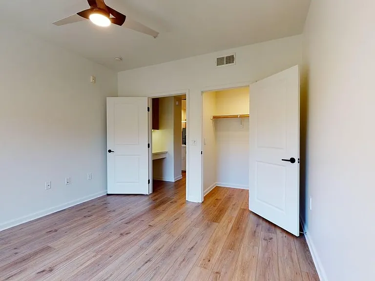 Spacious apartment bedroom with large closet and wood style floor.