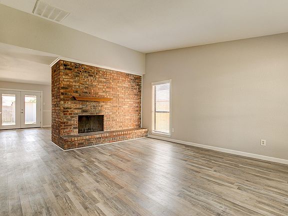 The spacious family room features a brick fireplace with a mantle and is open to the kitchen area.