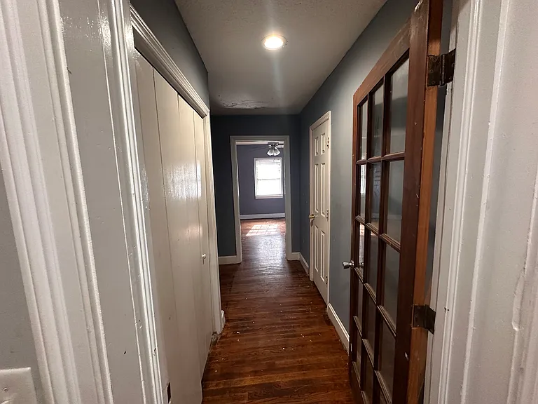 Entry from kitchen to hall, closed door to the right of the bathroom, doors on the left is a closet