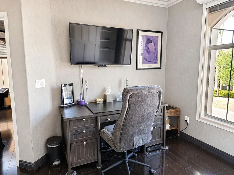 Dedicated home office nook features a built-in desk with drawers, wall-mounted TV, and a large window for outdoor views.