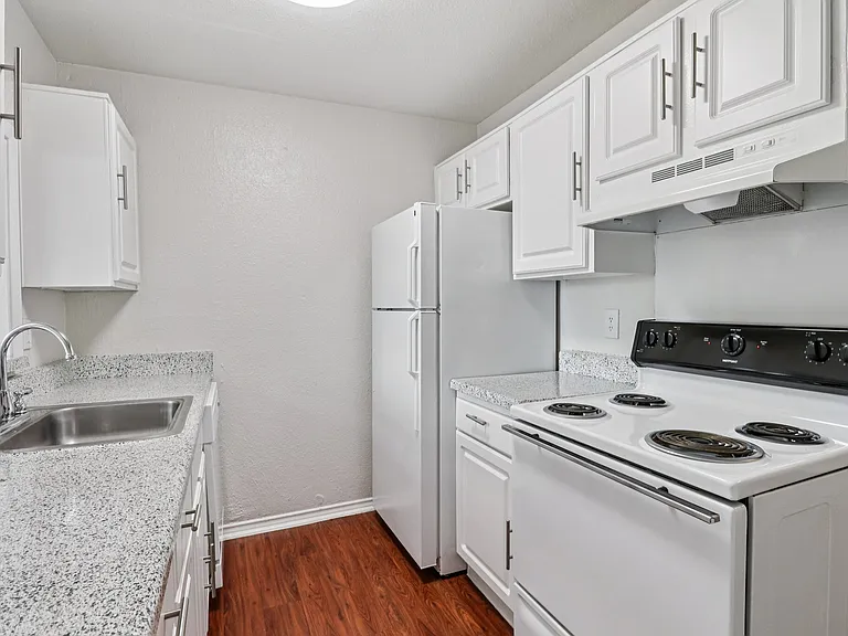 Modern kitchen with sleek white cabinets, speckled countertops, and wood-style flooring. Modern kitchen with sleek white cabinets, speckled countertops, and wood-style flooring.