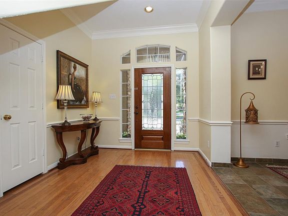 Front door is highlighted with transom windows and wood flooring.