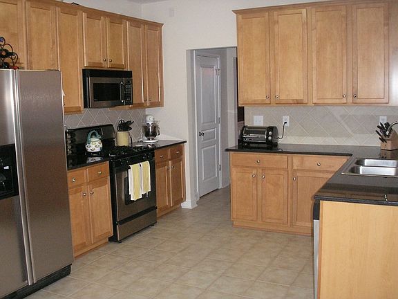 Kitchen w/ granite counters, tile backsplash, tile floors and SS appliances