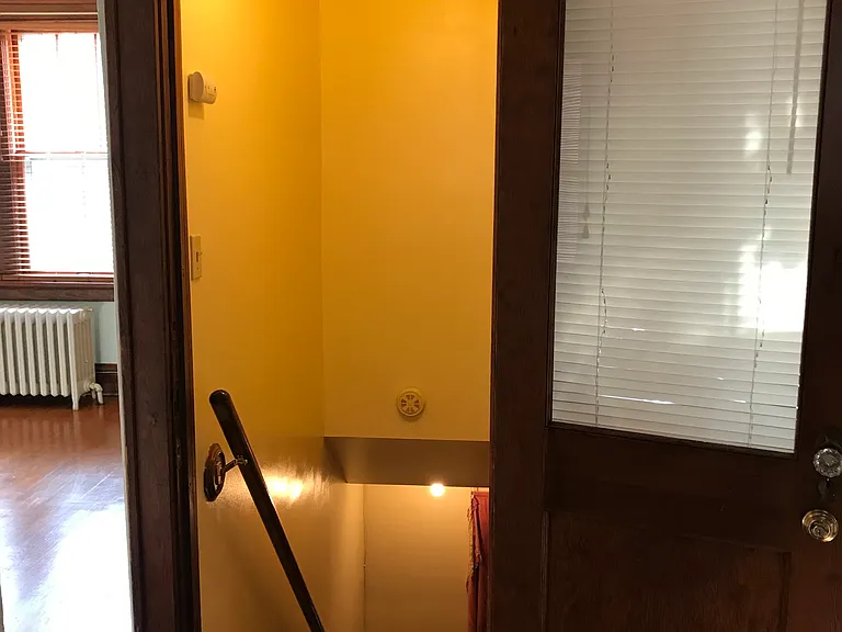Stairway to basement for laundry, and to the doorway where trash-recycling bins are accessible in the driveway