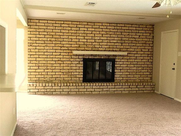 Large living area features a brick wall and wood burning fireplace.