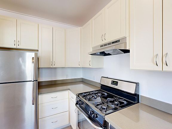 Bright modern kitchen featuring stainless steel appliances, cabinets, and a gas stove on a sleek countertop.