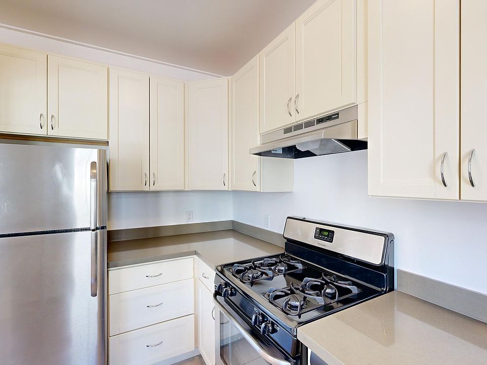 Bright modern kitchen featuring stainless steel appliances, cabinets, and a gas stove on a sleek countertop.