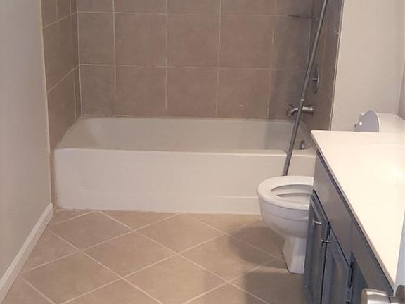 primary bathroom with custom tile work, double vanity, walk in closet