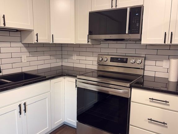 New stainless steel appliances including electric range, microwave, dishwasher and refrigerator.