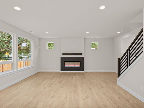 Spacious great room with warm welcoming fireplace and natural light from large windows.