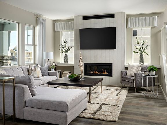 A modern and cozy living room with a fireplace, a large TV, and comfortable gray sofas arranged arou