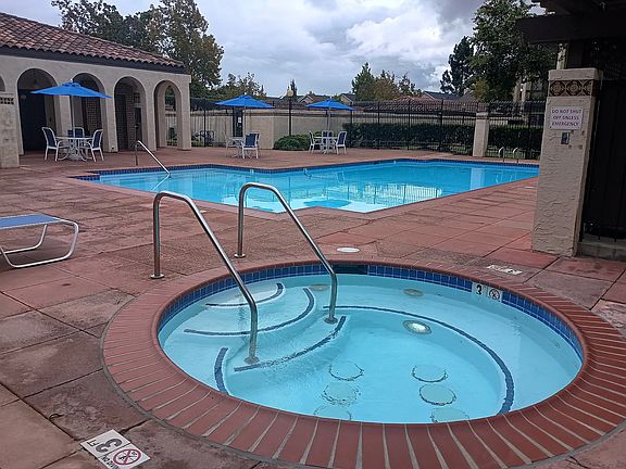Pool, jacuzzi and clubhouse area in background.