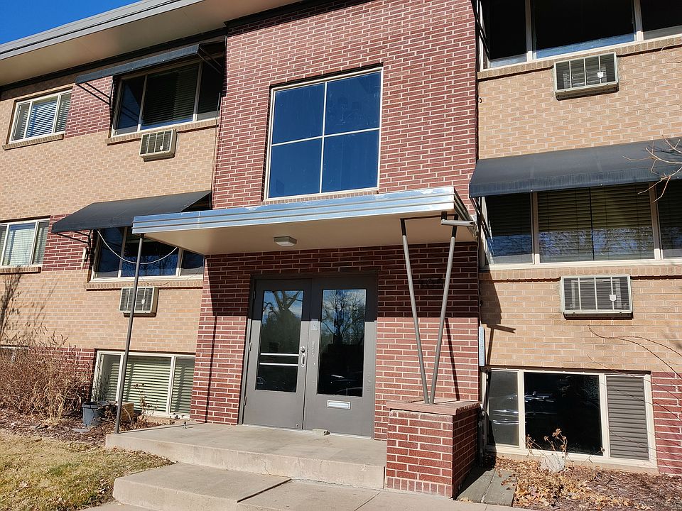 Charming brick apartment building with modern awnings and large windows, offering a warm and welcoming entrance.
