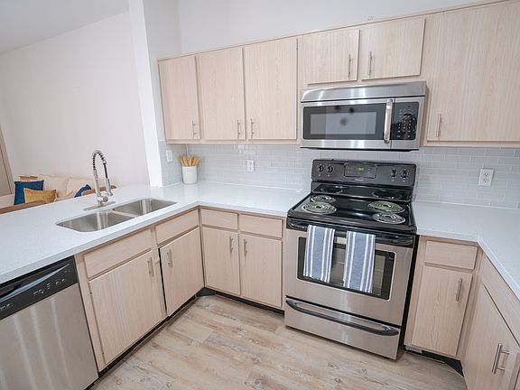 Kitchen w/ stainless steel appliances, quartz counters, and tile backsplash