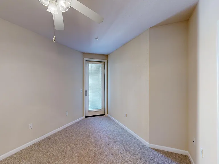 Spacious apartment bedroom with large closet and plush carpet flooring.