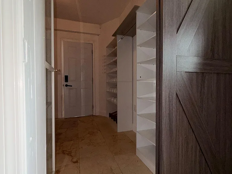 Dedicated storage area with built-in shelving and tiled flooring, ideal for organizing pantry items and household supplies.