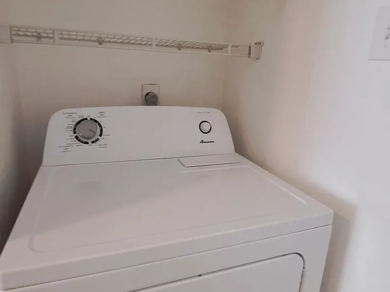 Dedicated laundry nook with in-home dryer and wire shelving above for convenient storage of supplies and linens.