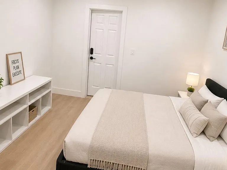 Bedroom features a full-size bed, nightstand lighting, and an open shelving unit for extra storage and display.