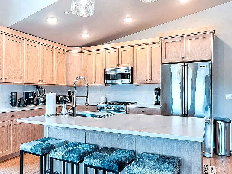 Kitchen island with undermount sink, white quartz countertop, and full stainless steel appliance suite including gas range