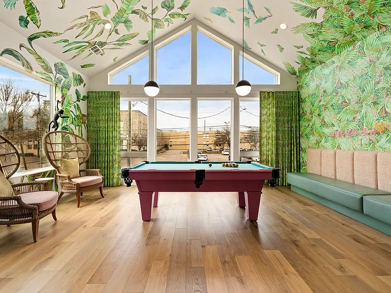 Expansive recreation space featuring a pool table, wood-finish flooring, and a vaulted ceiling with large windows