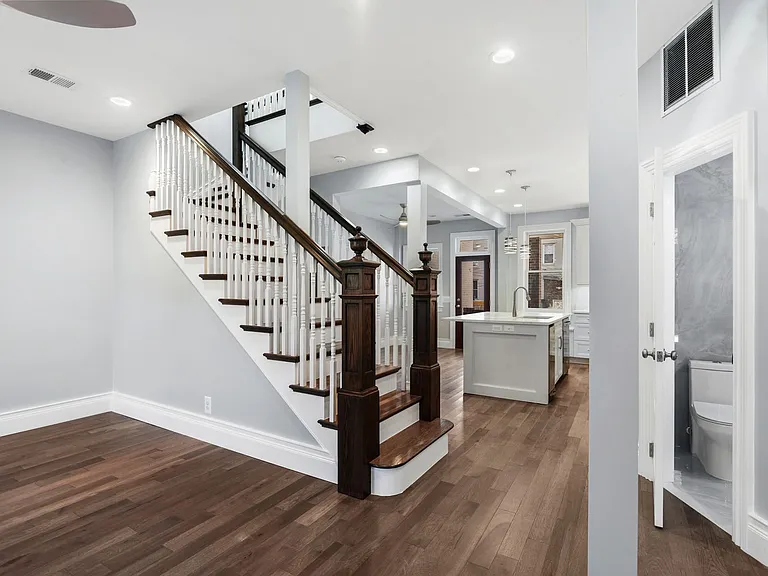view from front door highlighting living room, refabricated original stair posts, powder room, and kitchen