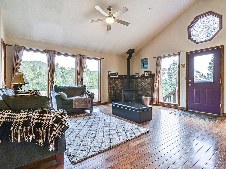 Living room open to kitchen and dining room. Hardwood floors, vaulted ceilings, floor to ceiling windows, and pellet stove!
