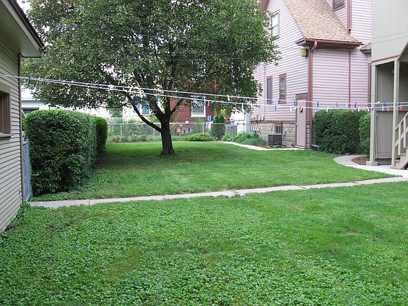 Large rear yard, shared by adjacent property we also own. Parking to the left of the hedge.