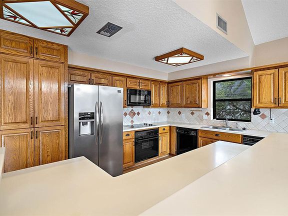 Eat-in kitchen has plenty of space for entertaining, large breakfast bar, ample cabinetry, built-in pantry & tile backsplash.