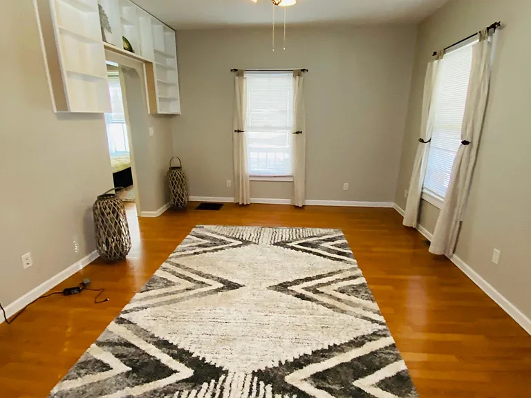 The Great room has a reversible ceiling fan, three windows with linen curtains and miniblinds, easy clean vinyl flooring, a storage closet, and a built-in display.