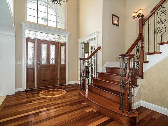 2 Story Entry Foyer with Brazilian in lay Wood flooring, Leaded Glass Front Door with Side Lights and Transom, Detailed Molding throughout.