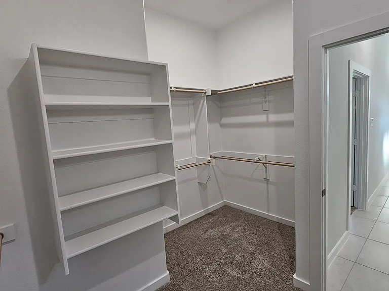 Massive walk-in primary closet with extensive built-in shelving and ample hanging space