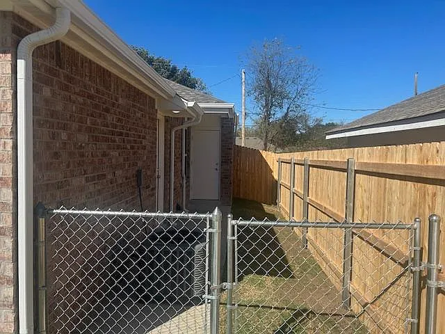 Small side yard with privacy fence, small storage closet on outside of unit.