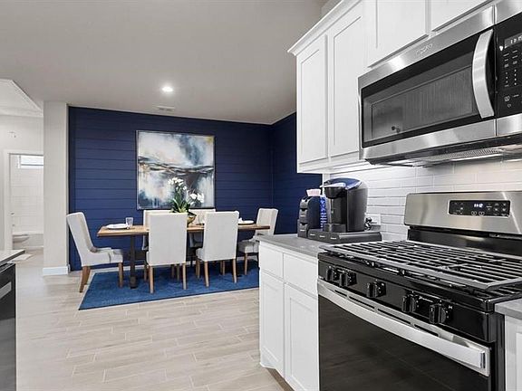 Kitchen featuring stainless steel appliances, white cabinetry, wood tiled floors, light stone countertops, and recessed lighting