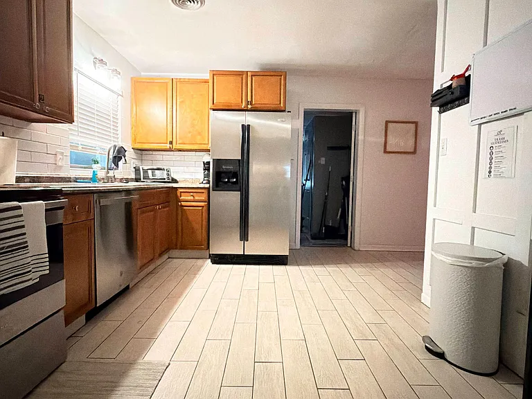 Spacious kitchen with ample cabinet storage, subway-tile backsplash, and stainless-steel fridge for everyday convenience.