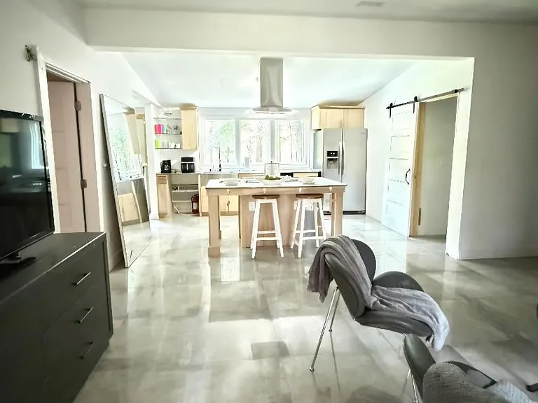 Open-concept kitchen with large island seating, stainless refrigerator, ample cabinetry, and wide tile flooring.