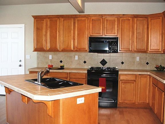 Kitchen features tile counters and backsplash along with top end appliances