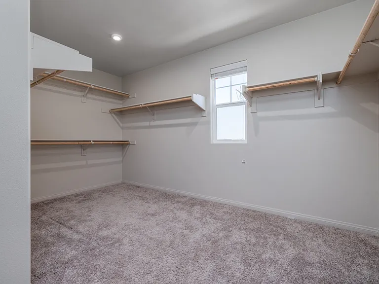 Spacious walk-in closet in the primary suite featuring built-in shelving and ample hanging space. Bright and airy with a window for natural light_offering plenty of room for organized storage and a true luxury feel in this modern Menifee home.