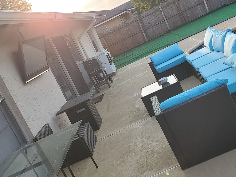 Backyard patio with poolside lounge seating, grilling area, and fenced yard for outdoor meals and relaxing.