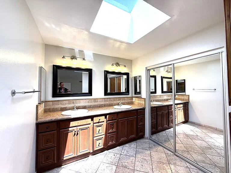 Primary bath with large walkin closet behind mirrored doors and skylight.