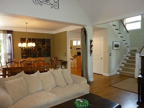 Living room and dining room feature a light open floor plan with hardwood floors, vaulted ceilings, 