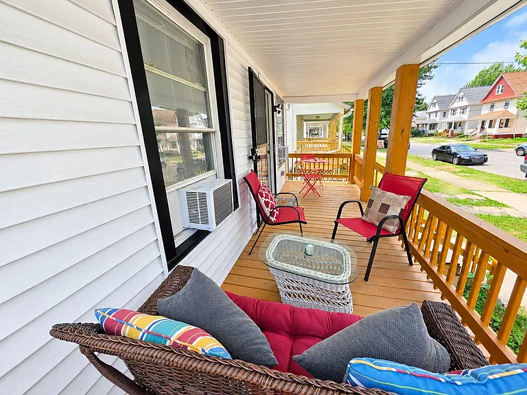 Covered front porch with comfortable seating and a small table, offering a relaxing spot to enjoy neighborhood views.