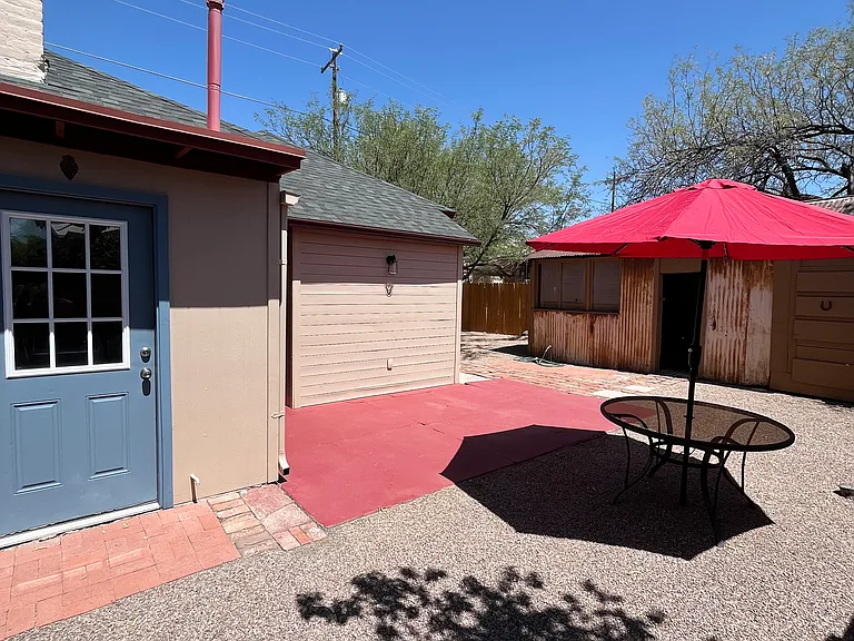 Laundry room with washer/dryer, storage building, back concrete patio. Table and new shade umbrella stay.