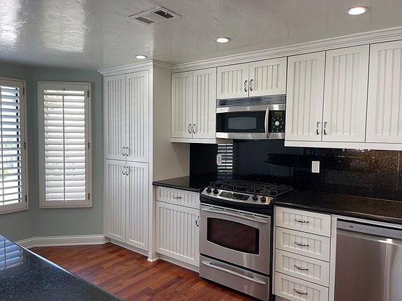 Kitchen with lots of windows, pantry, wine refrigerator, plantation shutters and hardwood floors.