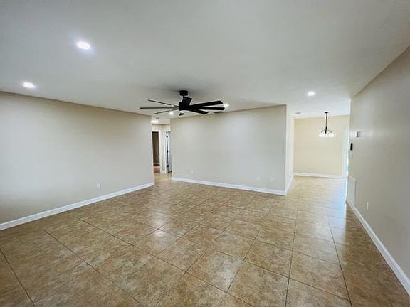 Large tiled living room with ceiling fan.