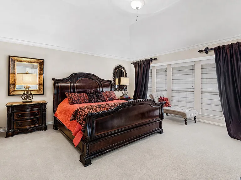 Spacious bedroom featuring light-toned carpeting and a vaulted ceiling with crown molding