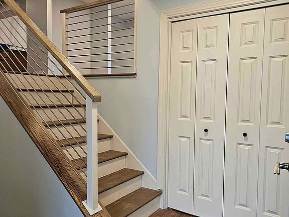 Welcoming entryway featuring updated flooring, modern staircase railing, and fresh neutral pain