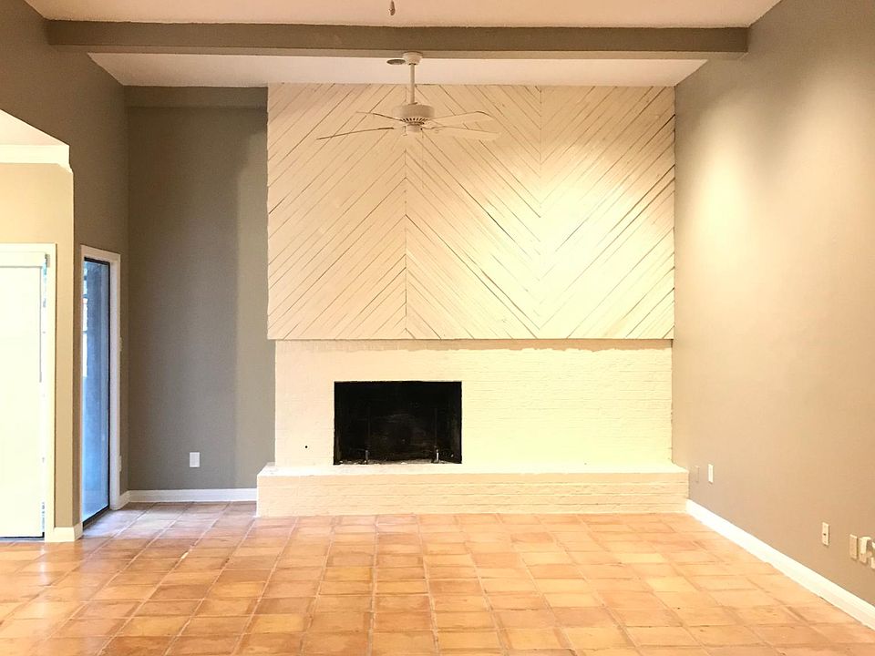 Stunning living room with Saltillo tile, vaulted ceilings, plenty of light and fans, a fireplace, and decorative beams!