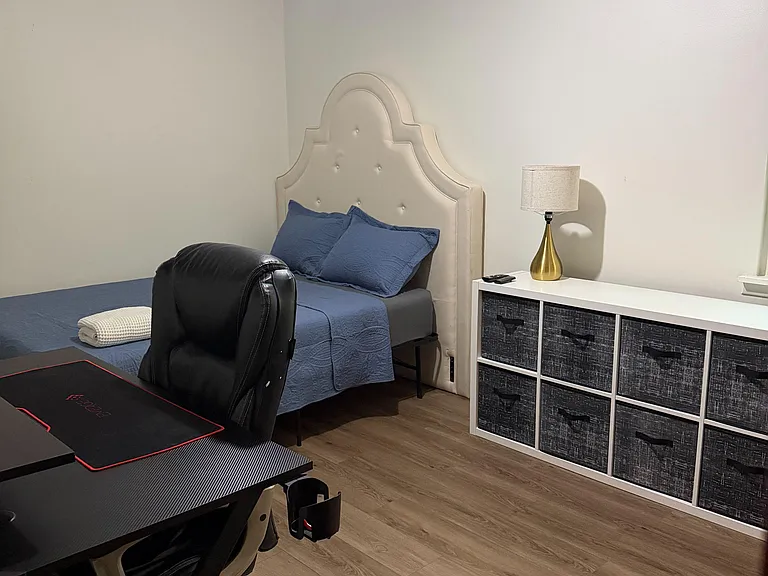 Furnished bedroom with a full bed, work desk, and dresser storage, set on durable wood-look flooring.