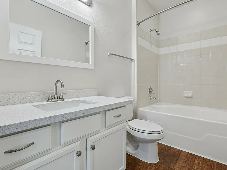 Elegant bathroom with modern fixtures, featuring a sleek quartz vanity, large mirror, and pristine bathtub with overhead shower. Elegant bathroom with modern fixtures, featuring a sleek quartz vanity, large mirror, and pristine bathtub with overhead showe