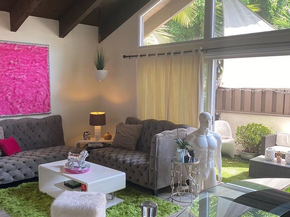 Living room with high vaulted beamed ceilings, a fireplace, luxury vinyl flooring, large windows and private patio.